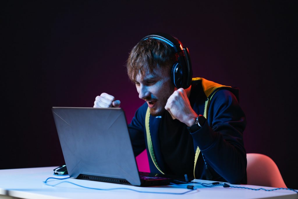 Guy gamer winner with headset playing video games on his personal computer